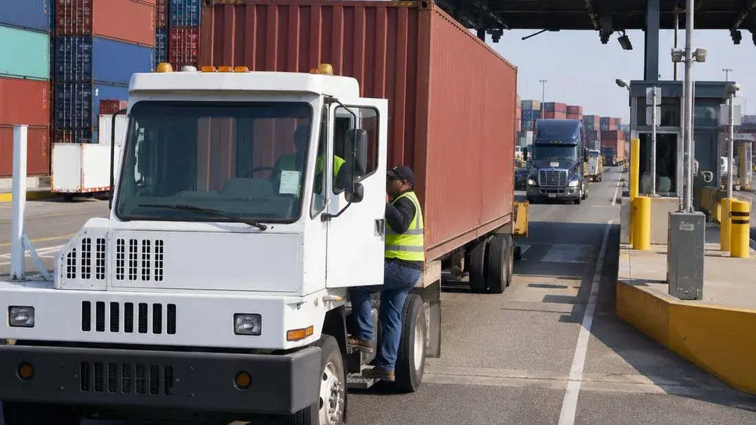 A yard truck hauling a container through an intermodal terminal gate checkpoint
